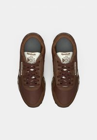 Par sivih Reebok Classic tenisica s tamnim vezicama, bijelom oznakom na jeziku i crnim unutarnjim oblogama, prikazanih odozgo na bijeloj pozadini.