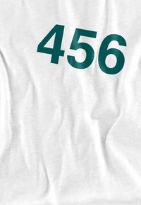 White t-shirt featuring large teal numbers "456" printed on the front. Fabric appears smooth with slight wrinkles.