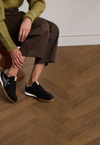 Sneaker nere in suede con tomaia testurizzata e suola in gomma, con un discreto motivo leopardato sul tallone e dettagli di branding rosa.