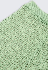 Gebreid groen kledingstuk met een open, afwisselend ruitpatroon. De geribbelde tailleband voegt textuur toe en creëert een lichte uitstraling.