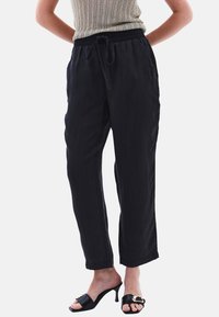 Svarta, lätta, löst sittande byxor med elastisk midja och dragsko, med sidofickor och en jämn textur.