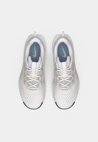 Ζεύγος καθαρών λευκών παπουτσιών Nike για τρέξιμο με ανοιχτές μπεζ λεπτομέρειες και μπλε εσωτερικές σόλες, σε άποψη από πάνω μπροστά σε απλό λευκό φόντο.