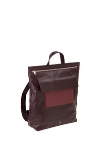 Zaino in pelle di un profondo color bordeaux, con flap e chiusura a zip, dotato di una tasca frontale con un pannello bordeaux a contrasto e spallacci regolabili.