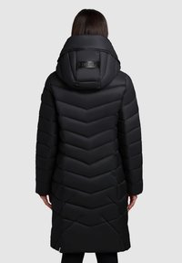 Black puffer coat with a chevron pattern, featuring a large, structured hood and branded accent on the back; smooth, shiny material.