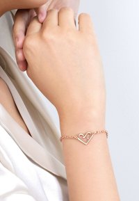 Pulsera de corazón en oro rosa con un dise�ño de eslabones, que presenta una forma de corazón abierto como el principal acento. Textura suave y acabado pulido.
