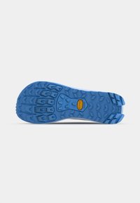 Vibram-Außensohle aus leuchtend blauem Gummi mit multidirektionalen Stollen für Traktion, mit einem gelben Logo in der Mitte.
