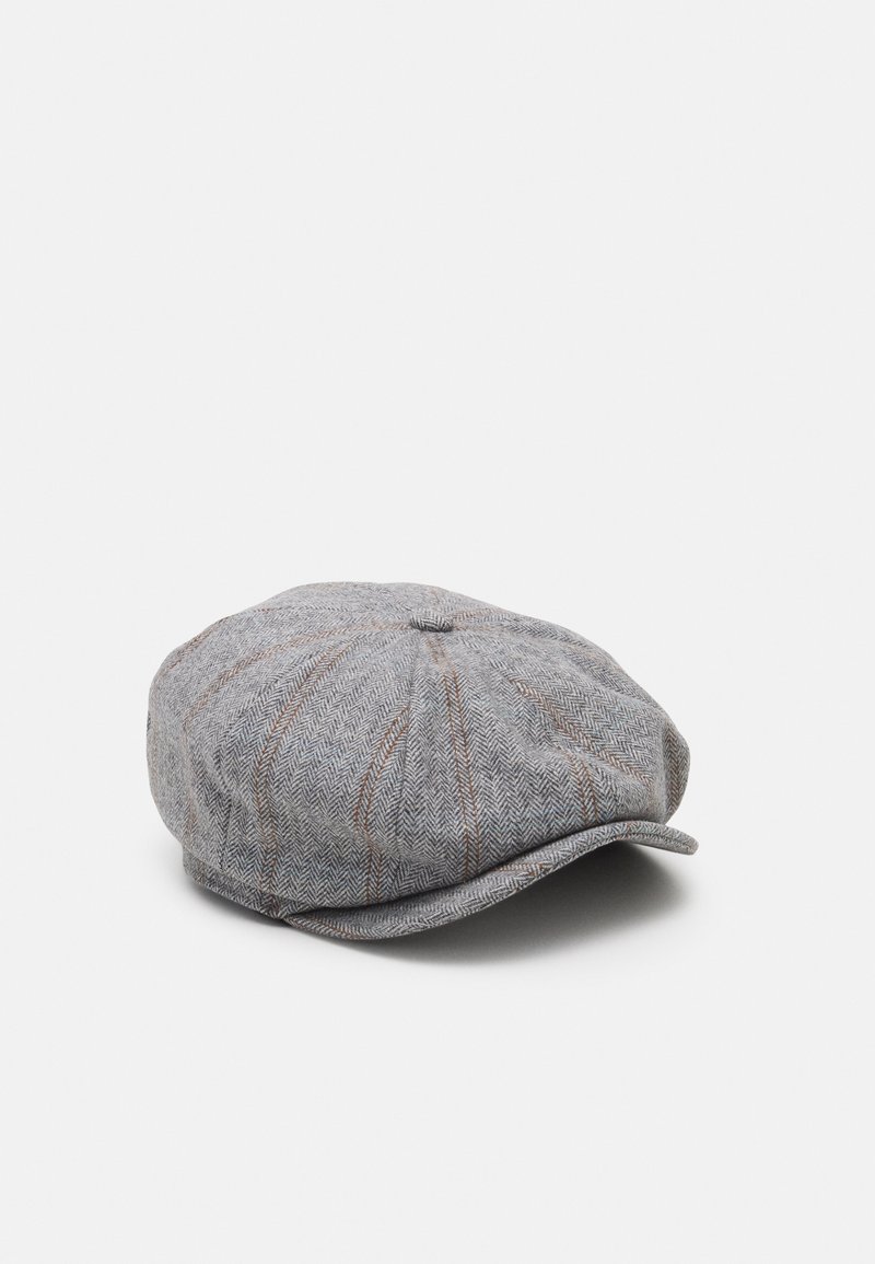 Casquette plate en tweed gris avec de subtiles rayures brunes et une petite visière, posée à plat sur un fond clair uni.