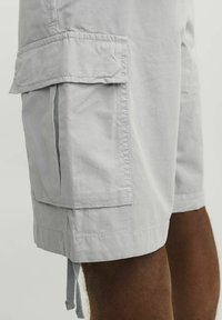 Shorts cargo gris clair en tissu léger, dotés de poches latérales, d'accents cousus et de cordons de serrage ajustables à l'ourlet.