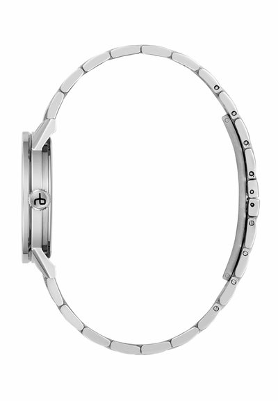 Bočný pohľad na strieborné kovové hodinky s prepojeným náramkom a korunou s logom na puzdre hodiniek.