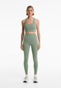 Ljusgrön sport-bh och matchande högmidjade leggings gjorda av stretchy tyg. Har en mjuk textur och minimalistisk design.