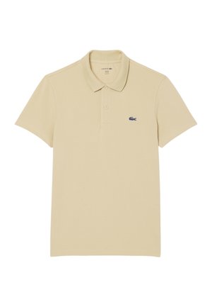 Polo beige de algodón, con cuello clásico, mangas cortas y un logo de cocodrilo azul marino en el lado superior izquierdo.