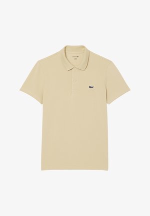 Polo beige de algodón, con cuello clásico, mangas cortas y un logo de cocodrilo azul marino en el lado superior izquierdo.