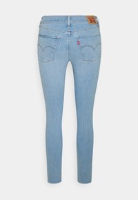 Jeans skinny de mezclilla azul claro con una cintura de altura media, bolsillos traseros con costuras en forma de corazón y una etiqueta de cuero con la marca.