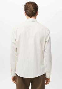 Camisa de botones de color claro con rayas verticales, cuello estándar y mangas largas con puños abotonados. Tejido liso y ligero.