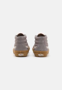 Grå suedhøje sneakers med polstret krave og tan gummisål, med en hvid stripe og 'Vans Off The Wall' logo på hælen.