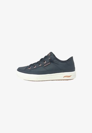 Sneakers sintetici blu navy con suola in gomma bianca, occhielli dorati e logo "SKECHERS". Punta arrotondata e tomaia testurizzata per una maggiore aderenza.