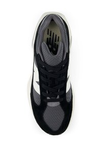 Baskets de sport grises et noires avec des accents blancs sur les côtés, tige en mesh, lacets noirs et un logo visible sur la semelle intérieure rembourrée.