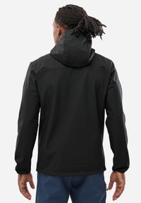 Veste softshell noire avec capuche, texture lisse, manches longues et poignets élastiques. Présente un ourlet droit et des détails de design minimalistes.