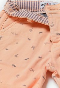 Pantaloni corti color pesca con un motivo di palme, pesci, occhiali da sole e tavole da surf, con una vita a righe e dettagli in ottone.