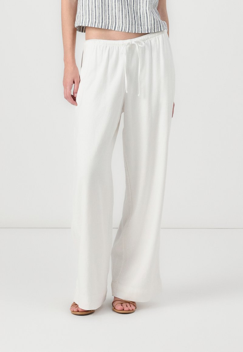 White, loose-fitting, lightweight pants with an elastic waist and drawstring. Flat seams and straight legs, ideal for casual wear.