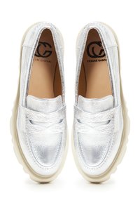 Metalen zilveren loafers met een gladde textuur, voorzien van een instapontwerp, contrasterende witte zool en decoratieve stiksels op de bovenkant.