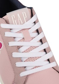 Light pink sneaker with white laces, textured leather and mesh detailing, featuring a clear tab labeled "GAP" on the tongue.