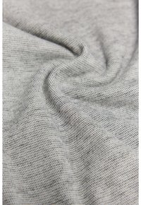 Tela gris texturizada con un patrón sutil, que muestra un acabado suave y liso. El material parece ligero y transpirable.