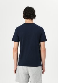T-shirt in cotone blu navy con colletto rotondo classico, maniche corte e una texture liscia. Cuciture visibili e un design semplice.