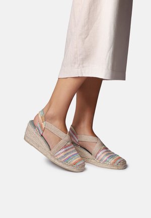 Sandały na koturnie z tkaninową cholewką o zygzakowatym wzorze w pastelowych kolorach, podeszwą z liny przypominającej sizal oraz elastycznymi paskami zapewniającymi wsparcie.
