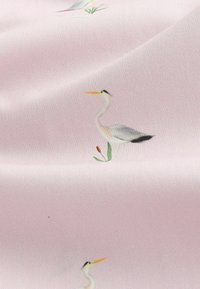 Tissu à motif avec des hérons sur un fond rose pâle, illustré en détail avec des oiseaux et des plantes vertes. Texture lisse.