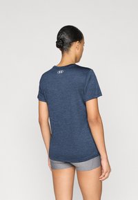 Αθλητική μπλούζα σε ναυτικό μπλε με κοντά μανίκια και στρογγυλή λαιμόκοψη, με μικρό λογότυπο στο πάνω μέρος της πλάτης. Λείο, ελαφρύ ύφασμα.