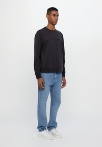Dark gray sweatshirt with a crew neckline, paired with light blue jeans and white sneakers. Simple design, no visible patterns or accents.