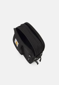 Borsa nera realizzata in materiale resistente, con due scomparti con zip, una tasca frontale e una patch con logo. Design compatto per un facile stoccaggio.