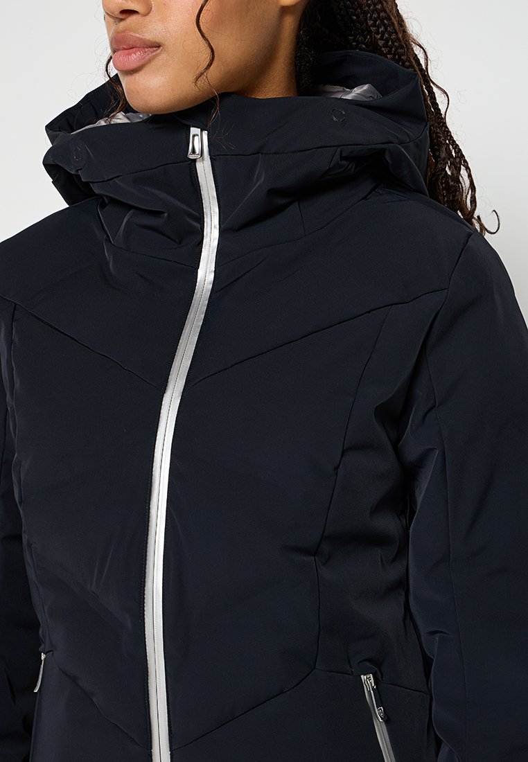 Marineblauwe geïsoleerde jas met een hoge kraag en zilveren rits, met gestikte patronen en ritszakken aan de zijkanten.