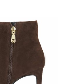 Close-up of dark brown suede ankle boot with a gold zipper and small high heel on a white background.