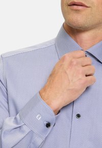 Light purple, textured dress shirt with a checkered pattern, featuring a classic collar and black buttons on the front and cuffs.