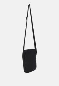 Borsa a spalla nera realizzata in tessuto, di forma rettangolare, con tracolla regolabile e una superficie liscia. Priva di accessori visibili.