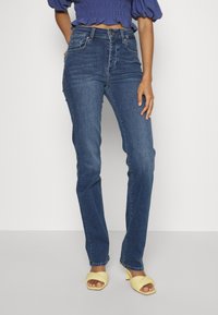 Tmavomodré džíny z denimu s vysokým pasem, rovným střihem nohavic a jemným vyblednutím na předních kapsách.