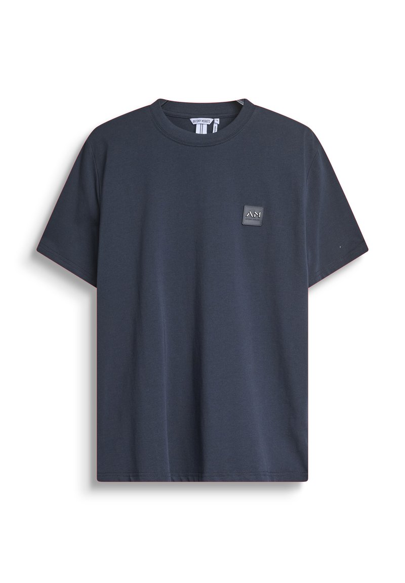 Camiseta de algodón de color azul marino con cuello redondo y mangas cortas. Presenta un pequeño parche con logo rectangular en el pecho. Diseño sencillo.