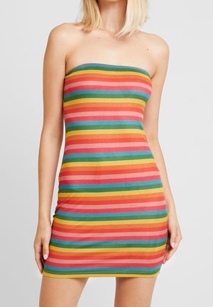 Donna che indossa un mini abito aderente senza spalline con strisce orizzontali in rosso, giallo, verde, blu e rosa su sfondo uniforme.