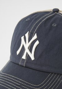 Gorra de béisbol color navy con el logotipo "NY" bordado en blanco. Presenta acentos cosidos y un ala curvada. Está hecha de un tejido texturizado.