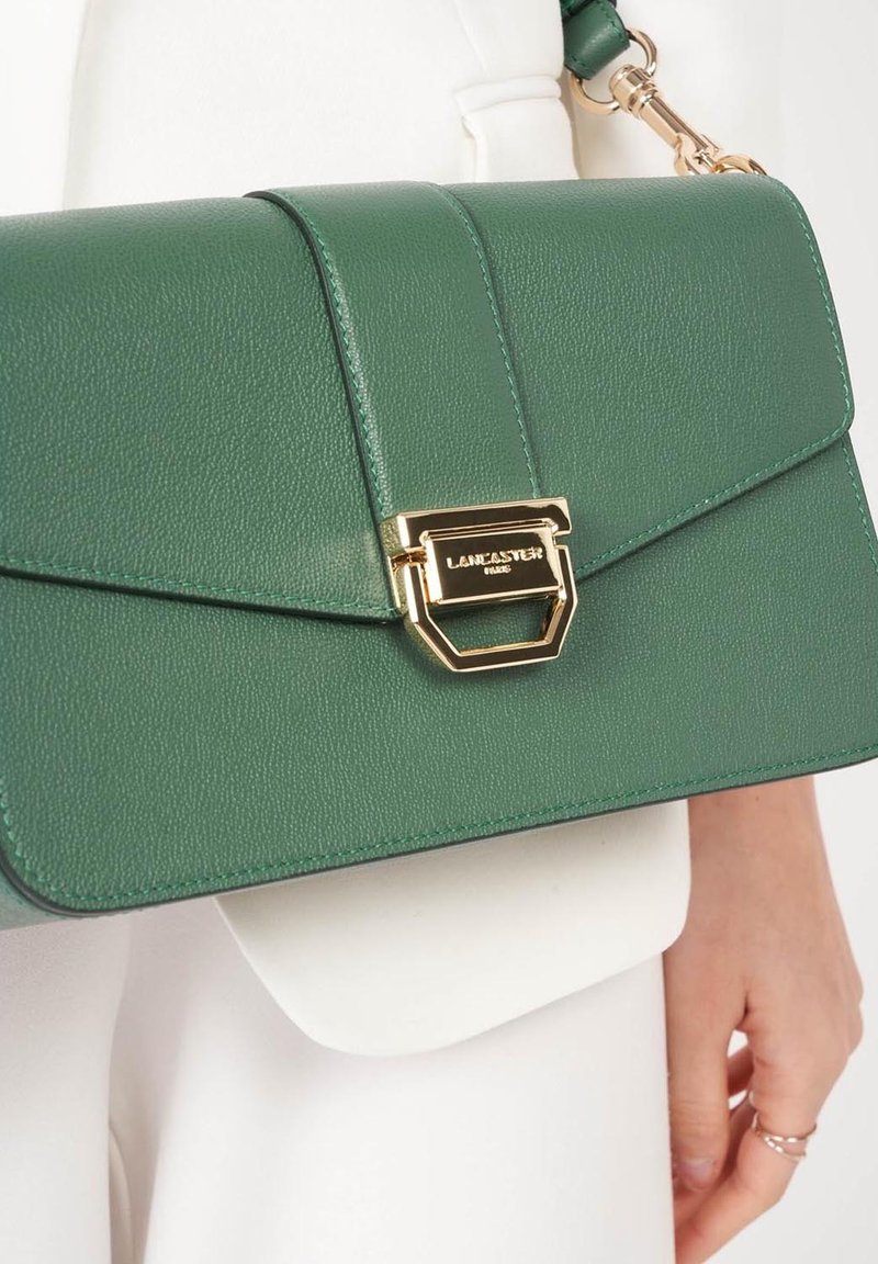 Borsa a tracolla in pelle verde con texture, dotata di una chiusura in hardware dorato, caratterizzata da un design a pattina triangolare e una tracolla regolabile per un utilizzo versatile.