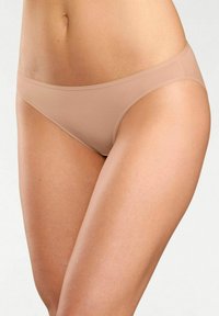 Slip bikini in microfibra beige con design senza cuciture, vita bassa e texture liscia, caratterizzato da una costruzione minimalista e assenza di segni visibili.