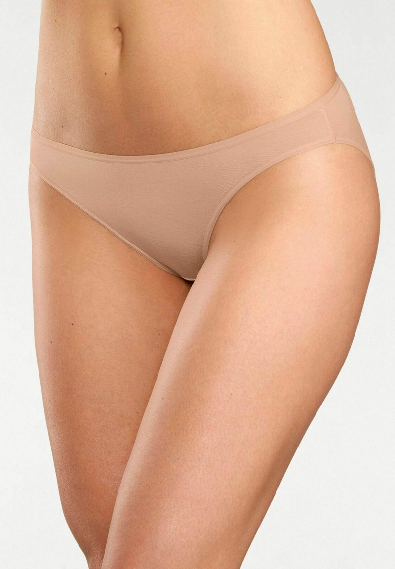 Slip bikini in microfibra beige con design senza cuciture, vita bassa e texture liscia, caratterizzato da una costruzione minimalista e assenza di segni visibili.