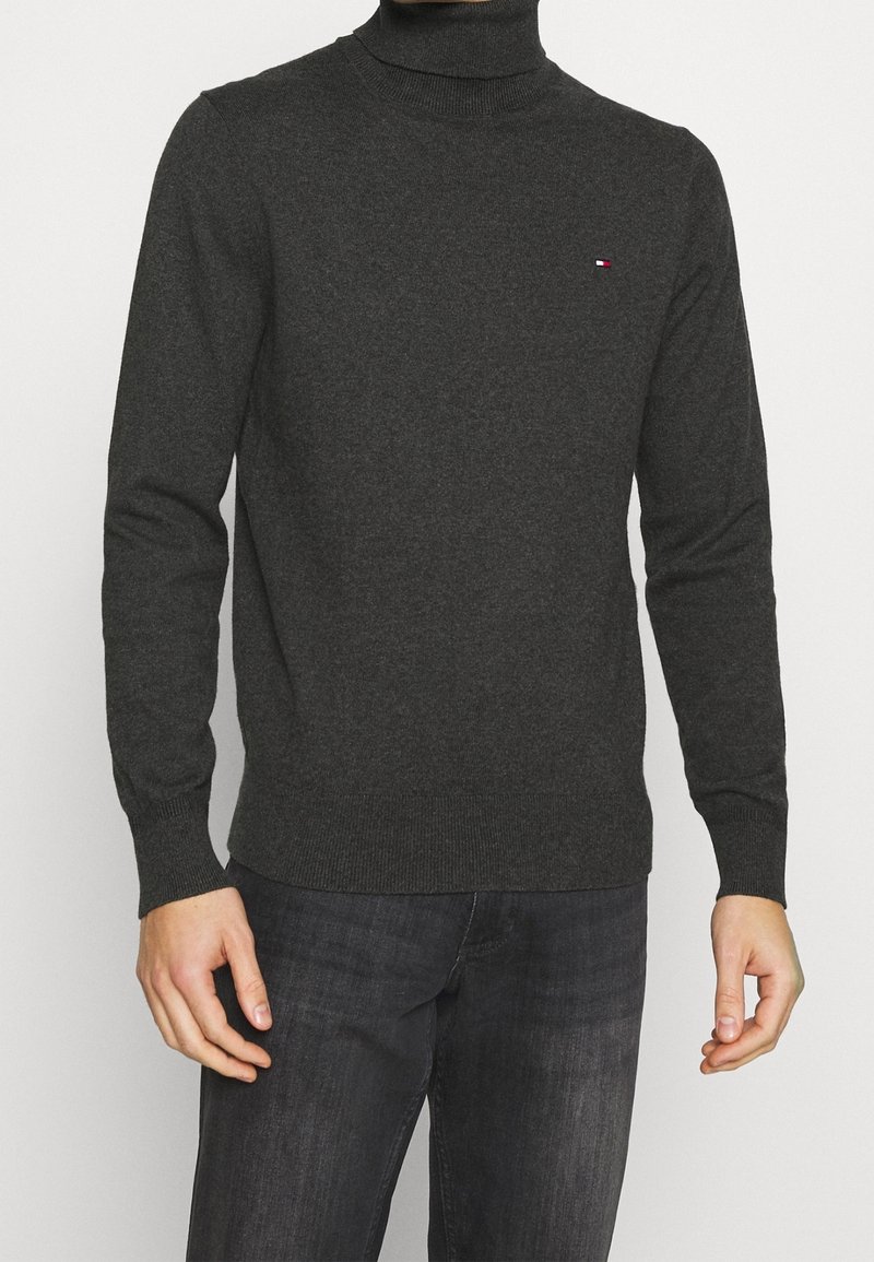 Maglione a collo alto grigio scuro realizzato in tessuto morbido. Caratterizzato da maniche lunghe e bordi a costine. Piccolo dettaglio del logo sul petto.