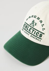 Groene en witte honkbalpet met geborduurde tekst "A's Baseball Athletics." Beschikt over een gebogen rand en textiel met structuur.