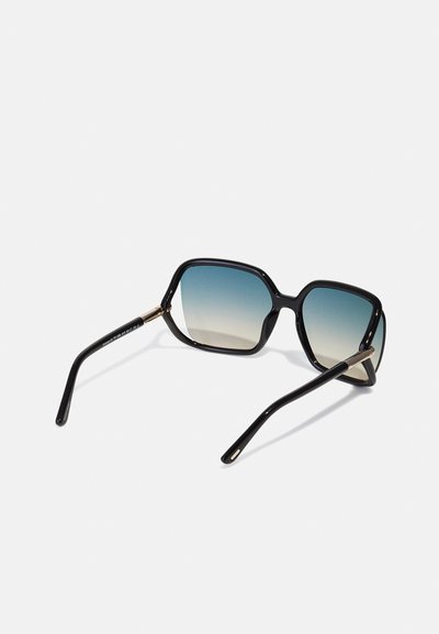 Occhiali da sole oversize neri con lenti blu sfumate. Forma angolare, montatura in plastica spessa, dettagli in tonalità oro sulle tempie.