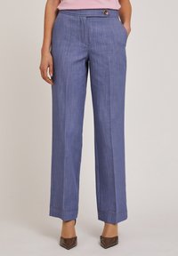 Lichtblauwe linnen broek met een rechte pijp, voorzakken en een knoopdetail bij de taille. Heeft contrasterende stiksels aan de zoom.