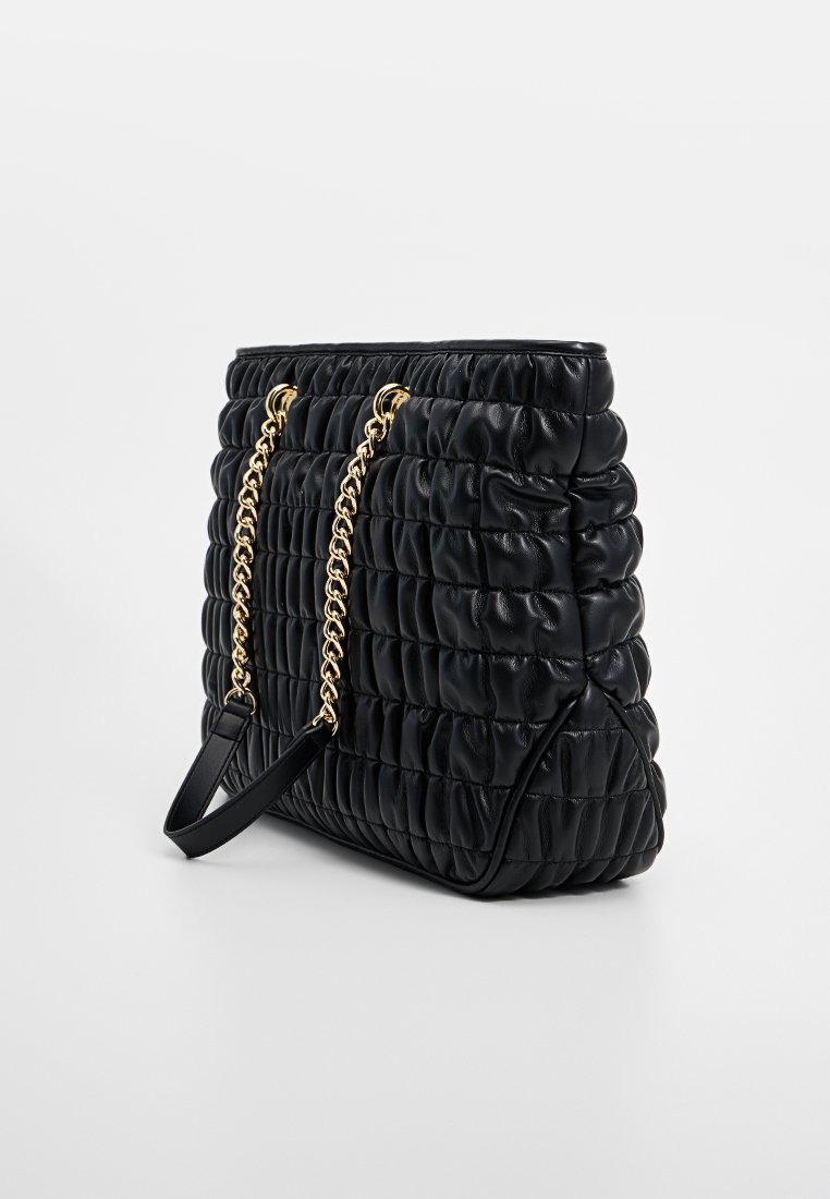 Borsa a tracolla nera trapuntata in pelle, con una tracolla in metallo dorato e un design testurizzato e morbido. La vista laterale mostra una forma strutturata.