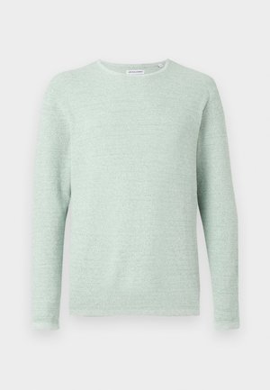 Gaiši zaļš adīts krekls ar apaļu kakla izgriezumu, garām piedurknēm, teksturētu audumu un brīvu piegriezumu. Nav redzamu rakstu vai rotājumu.